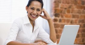 Businesswoman in office with laptop laughing