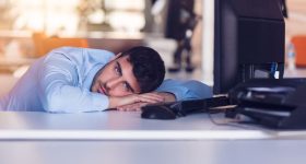 Portrait of a depressed office worker laying on his desk and thinking