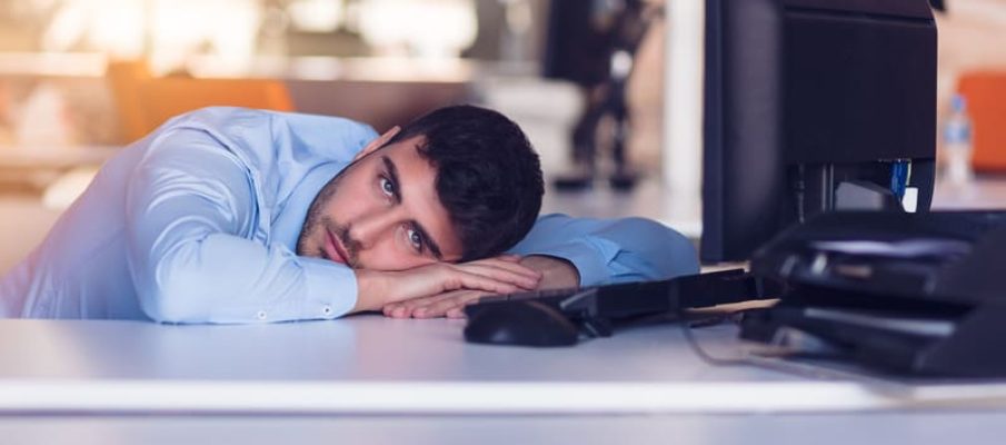 Portrait of a depressed office worker laying on his desk and thinking