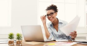 Happy business woman reading document at office desktop