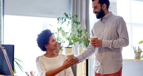 happy man bringing coffee to woman in office