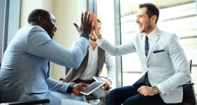 Happy successful multiracial business team giving a high fives gesture as they laugh and cheer their success.