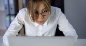 Overworked girl staring at computer screen, eyes wide open, working hard