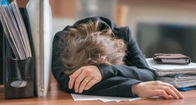 Tired and exhausted workaholic woman sleeping on desk in office.